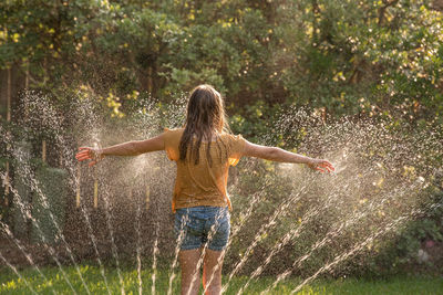 Girl plays in a sprinkler during summer