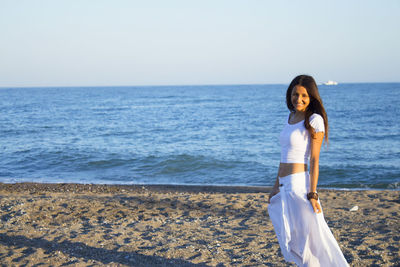 Woman standing on beach against clear sky