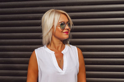 Portrait of blonde in sunglasses on background of brown blinds shutters garage house