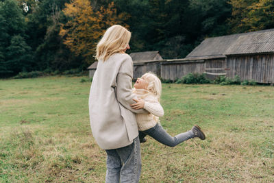 Mom circles her little daughter during a walk on the farm.