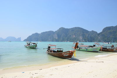 Boats moored on beach against clear sky