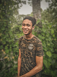 Portrait of young man standing against trees