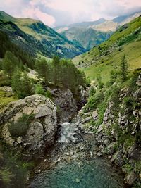 Scenic view of stream amidst mountains against sky