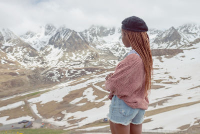 Rear view of woman standing on snowcapped mountain
