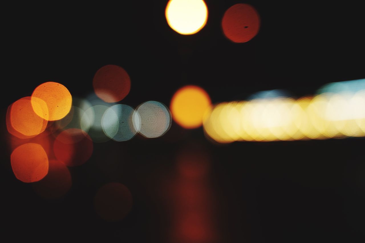 DEFOCUSED IMAGE OF ILLUMINATED LIGHTS ON STREET