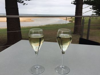 Close-up of wine glasses on table against sea