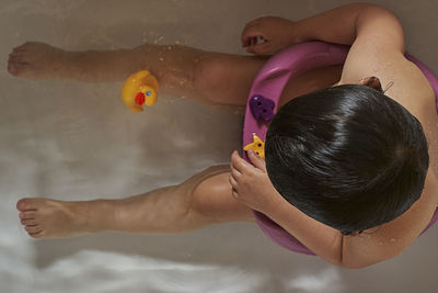 Happy baby playing with soap foam in home bathroom. rubber duck in foam bath.