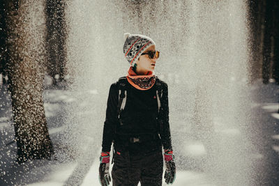 Woman looking away while standing outdoors during winter