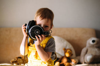 Funny little child having fun with headphones at home, portrait.