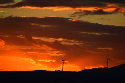 Low angle view of silhouette windmills against sky during sunset