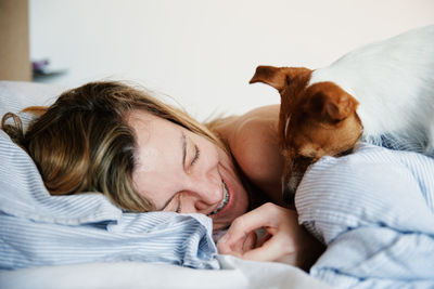 Woman sleeping in bed and play with her dog