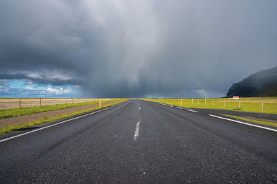 Scenic view of empty road in valley amidst green landscape against cloudy sky