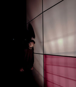 Man looking away while standing against wall