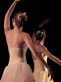 Female ballet dancers dancing against black background