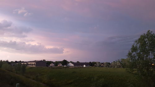 Houses and trees on field against sky