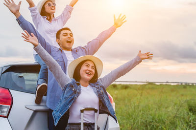 Happy young woman with arms raised against sky