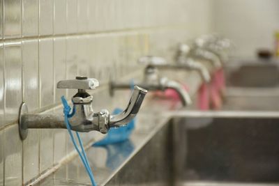 Close-up side view of taps on tiled wall