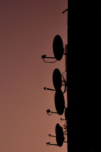 Low angle view of silhouette telephone pole against sky during sunset