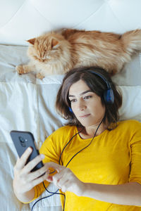 Young woman using mobile phone on bed at home