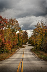 Road amidst trees against sky during autumn