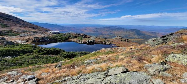 Pond on top of mt washington, blue sky and blue water, mountain ranges seen at the back