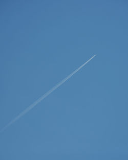 Low angle view of vapor trail against clear blue sky