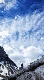 Low angle view of man standing on rock against sky