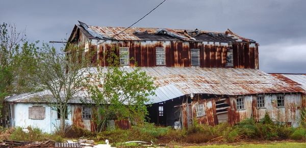 Exterior of abandoned house on field against sky