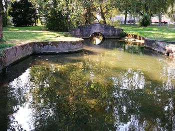 Arch bridge over river against trees