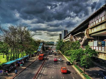 Road passing through city against cloudy sky