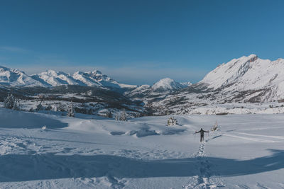 An unrecognizable male hiker wearing snowshoes walking in the french alps