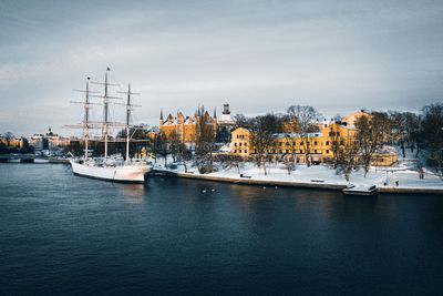 Sailboats moored in harbor against sky in city