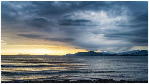 Scenic view of sea against dramatic sky during sunset