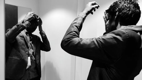 Man adjusting hair in front of mirror