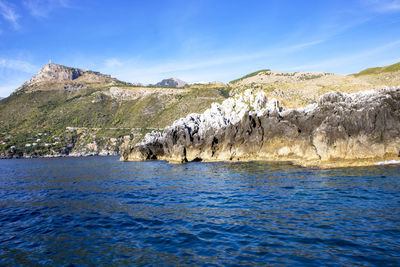 Scenic view of sea and mountains against blue sky