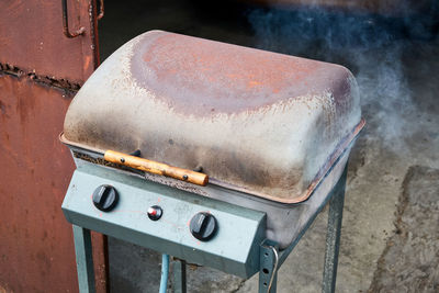Rusty barbecue lit with closed lid and smoke coming out