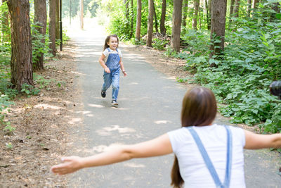 Rear view of friends on street amidst trees