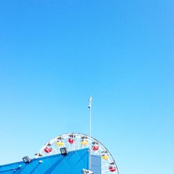 Low angle view of ferris wheel against clear blue sky