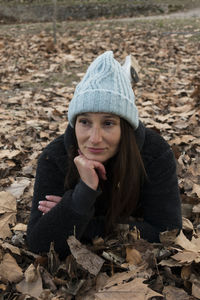 Thoughtful woman lying on autumn leaves