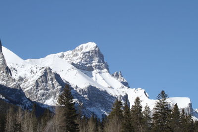 Low angle view of snowcapped mountains against clear blue sky