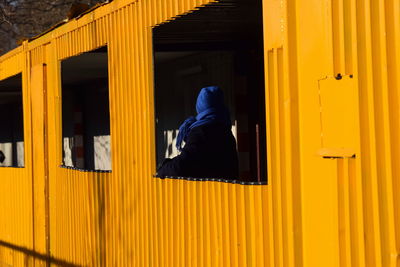 Low section of woman standing against yellow wall