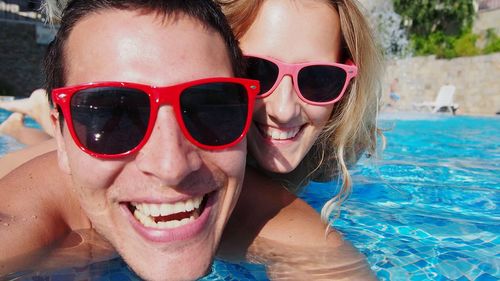 Close-up portrait smiling couple swimming in pool