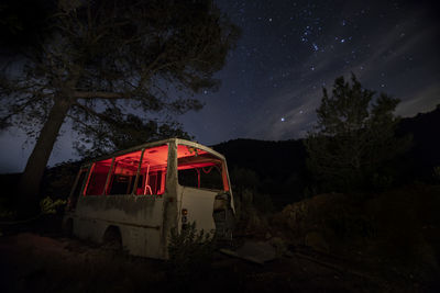 Red car on land against sky at night