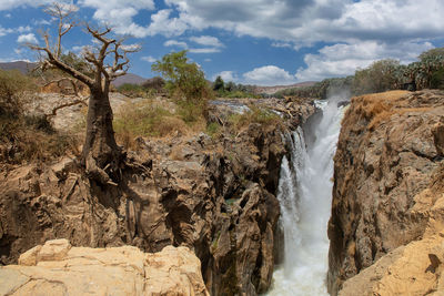 Scenic view of waterfall against sky