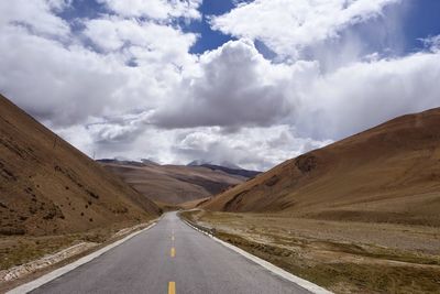 Empty road amidst landscape against sky