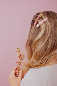 Woman holding pink flower against white background