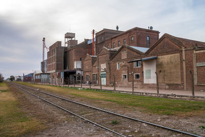 Railroad tracks by buildings in city against sky