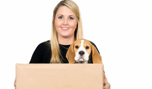 Portrait of young woman with dog against white background