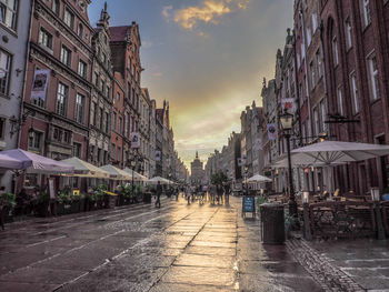 Street amidst buildings against sky at sunset