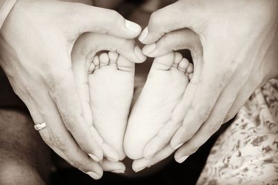 Parents making heart shape on baby foot with hands